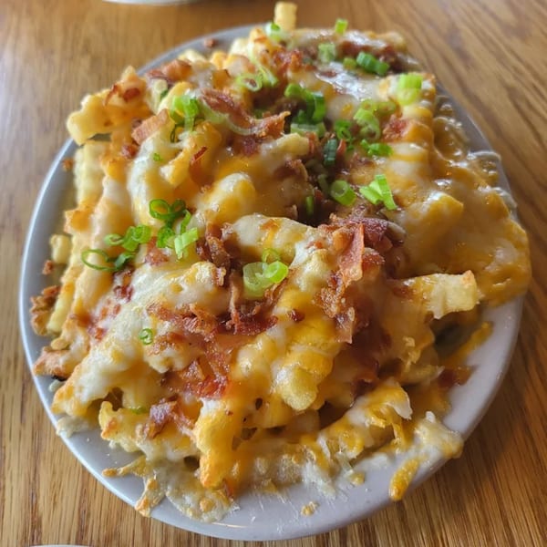 Loaded waffle fries from The Mettle Grill, topped with melted cheese, bacon, and green onions.